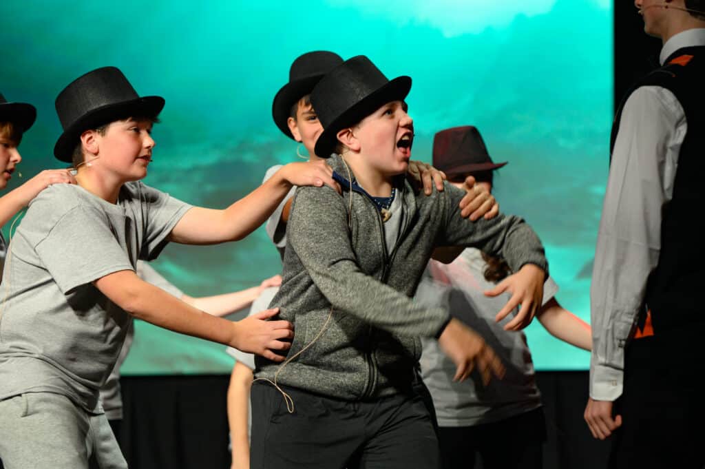 young boys with top hats on stage