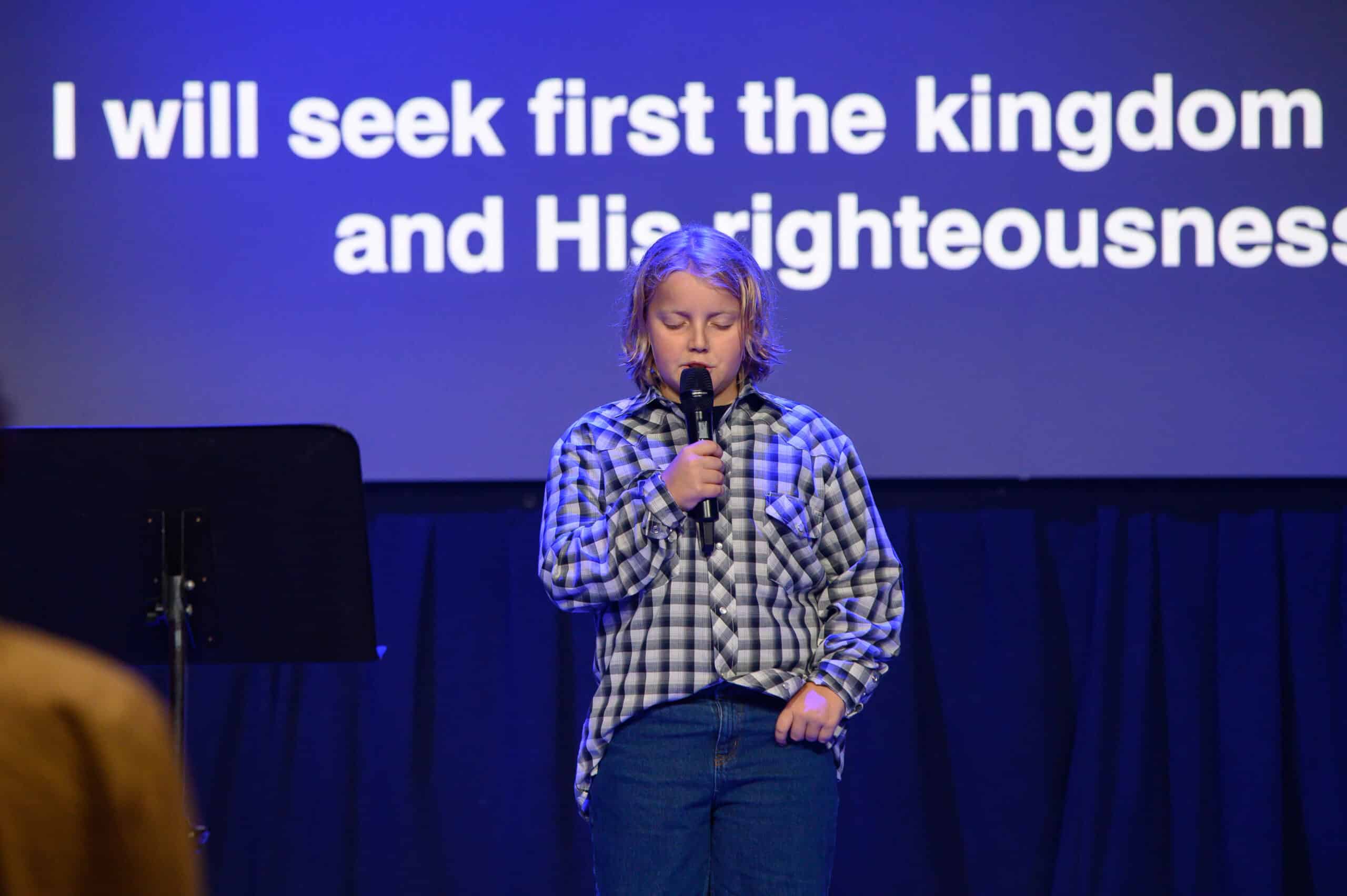 young child praying on stage