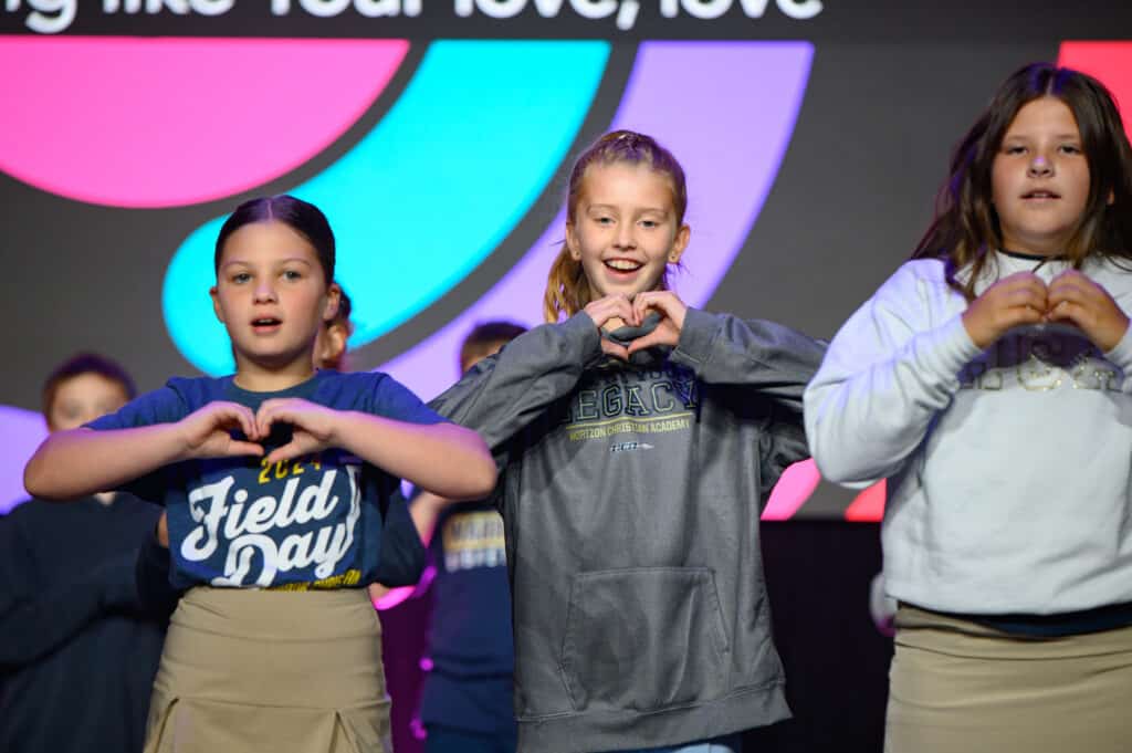 three female students gesturing a heart with their hands