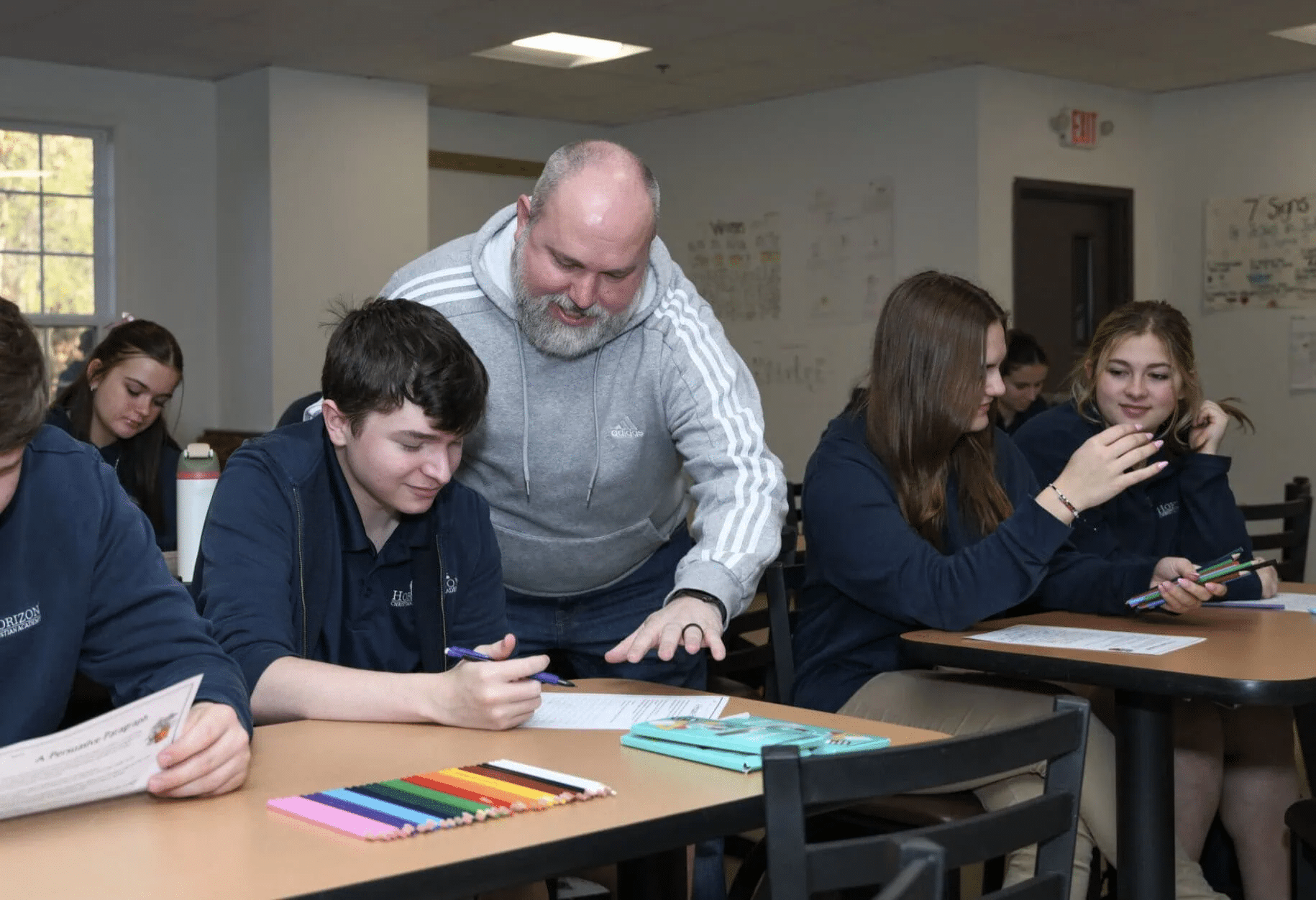 male teacher looking over students shoulder helping with school work