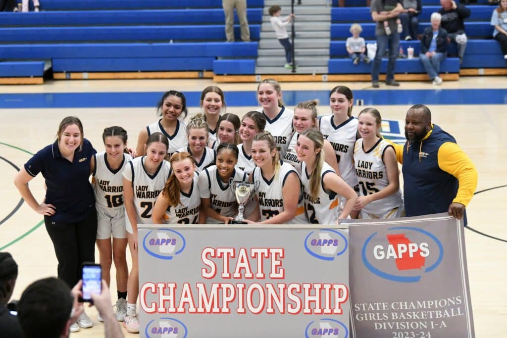 HCA girls basketball team photo with state championship banner