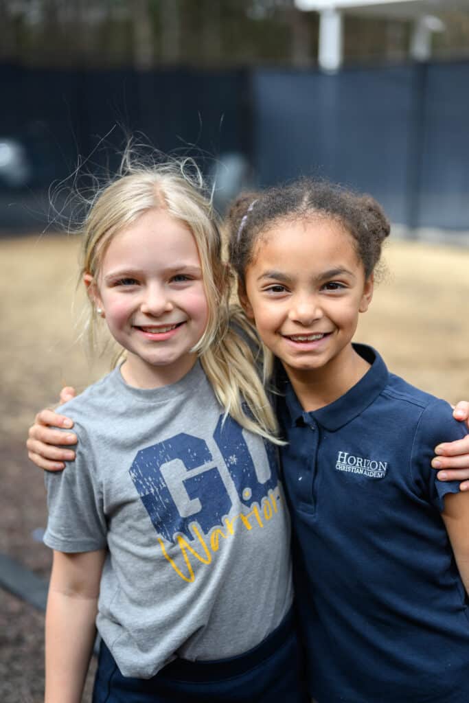Two girl HCA elementary students with arms around each other