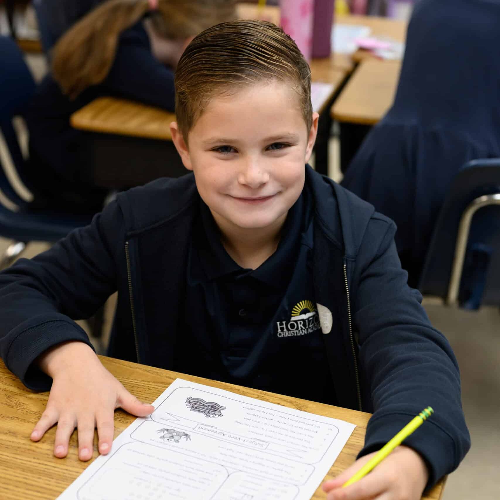 Elementary boy student at desk wearing HCA uniform
