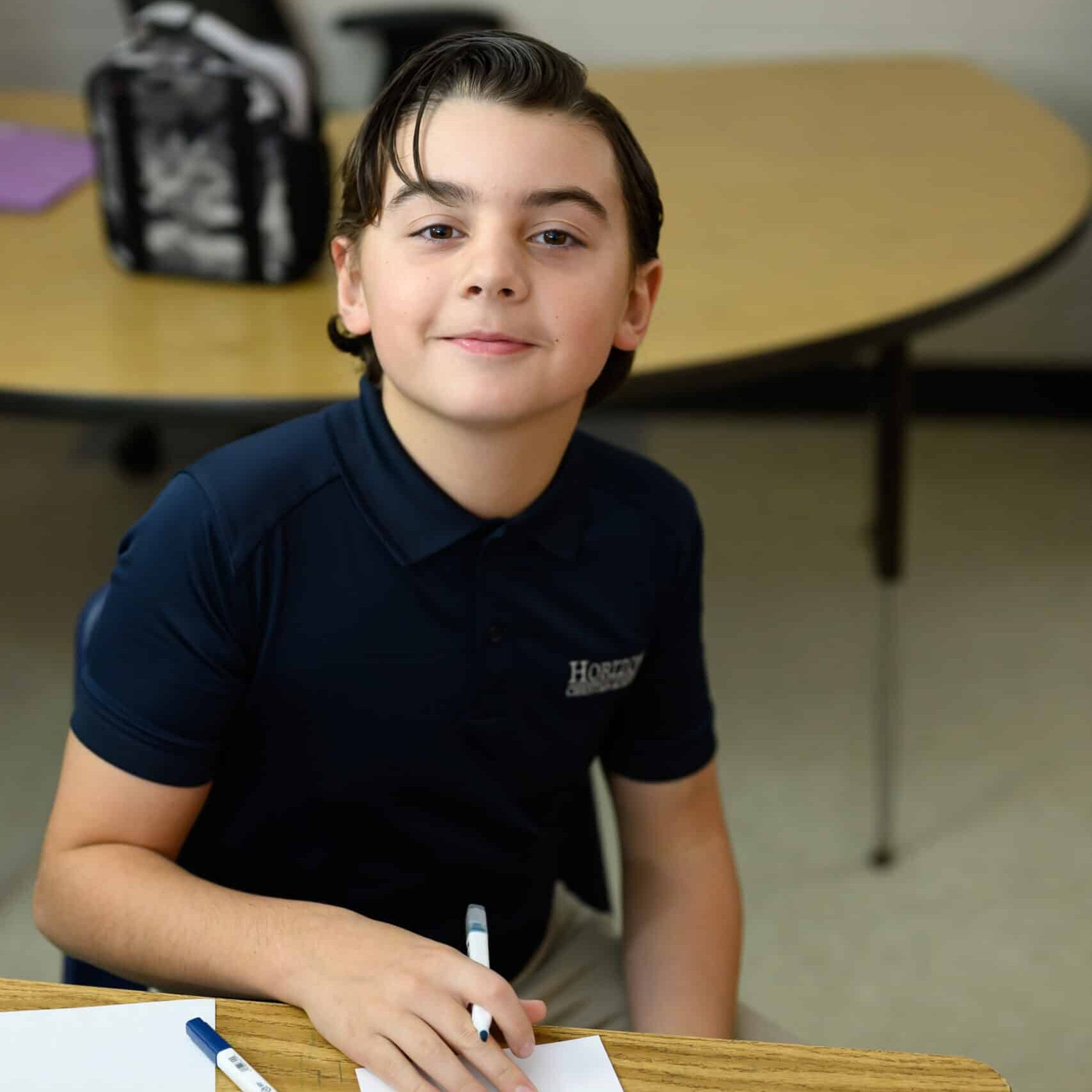Elementary boy student at desk wearing HCA uniform