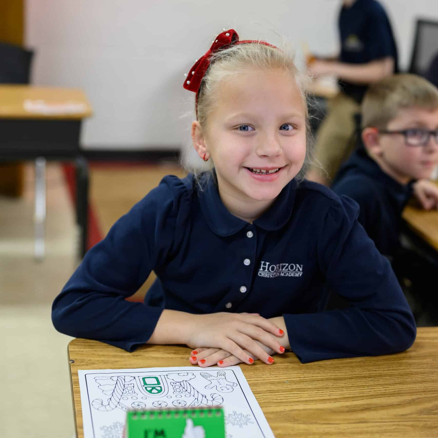 Elementary girl student at desk wearing HCA uniform
