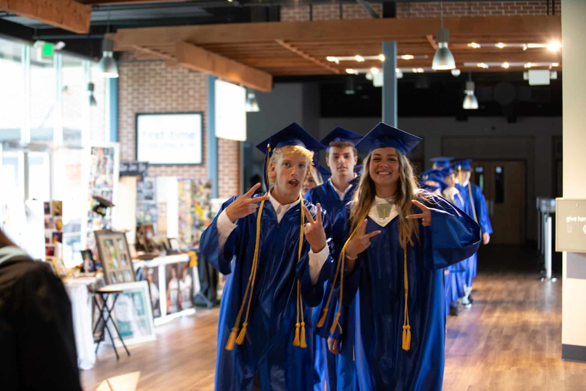 HCA graduates in cap and gown smiling for camera