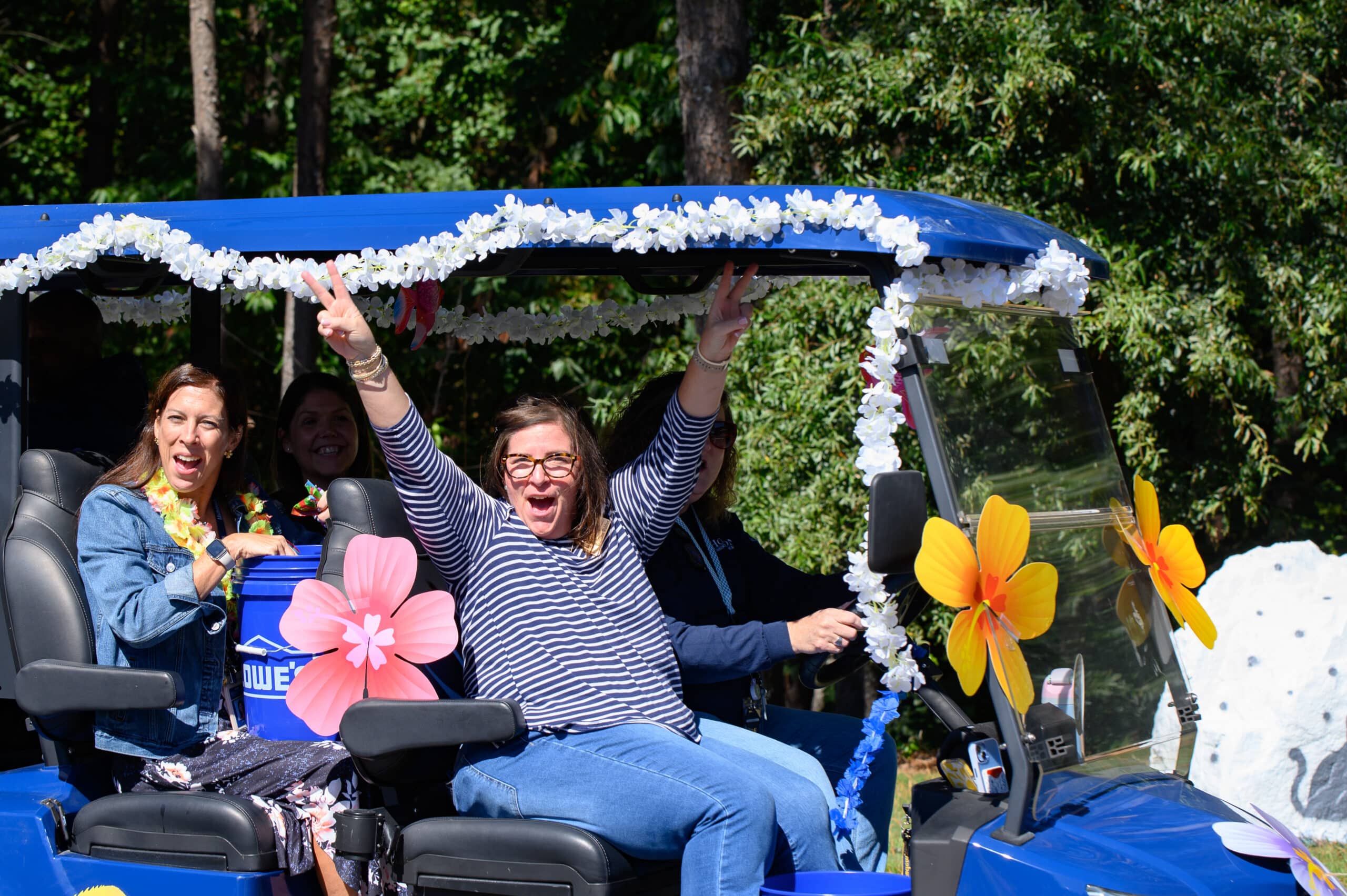 HCA staff on golf cart decorated with Hawaiian flowers