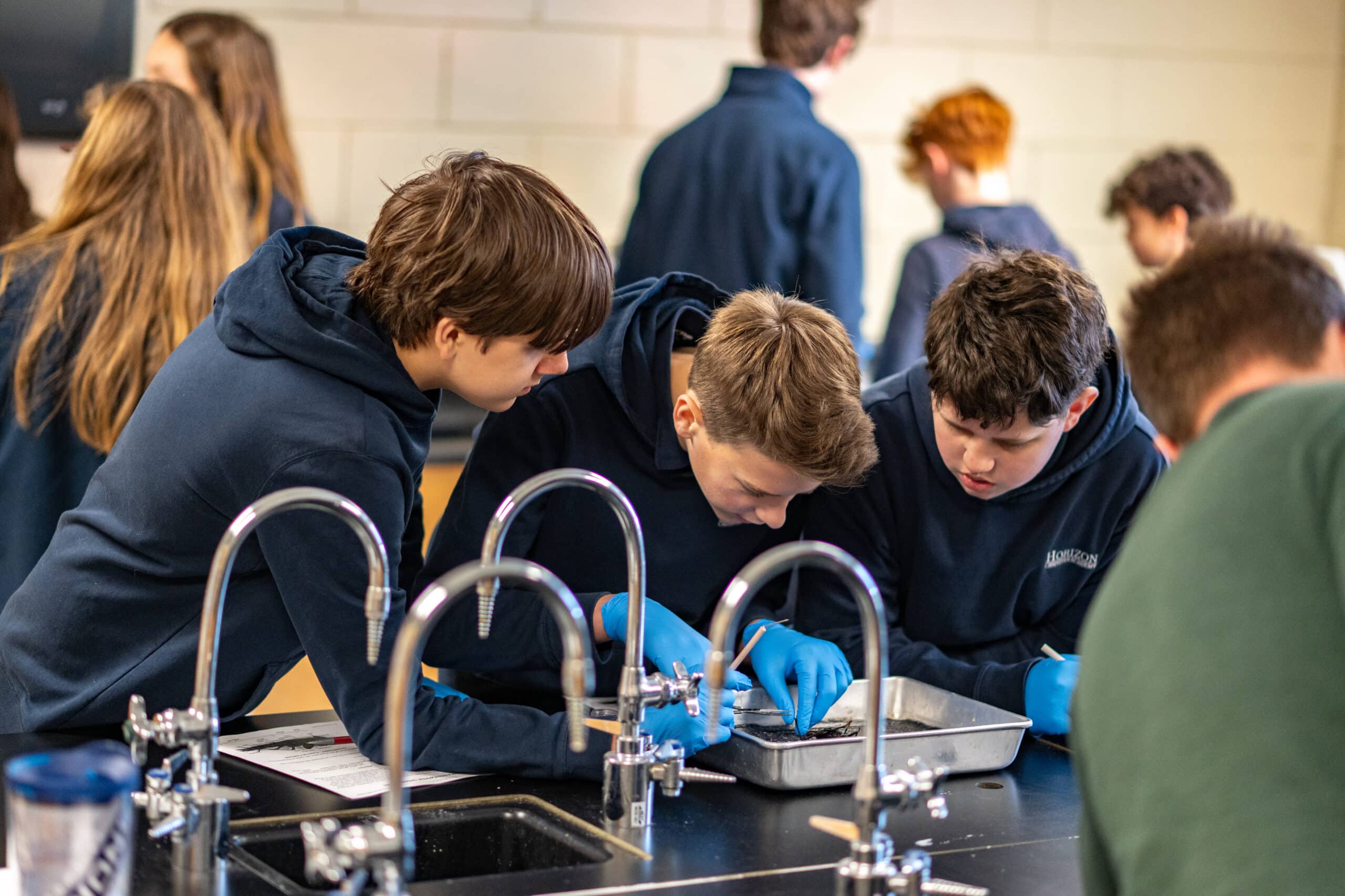 Three HCA students in biology class doing a dissection