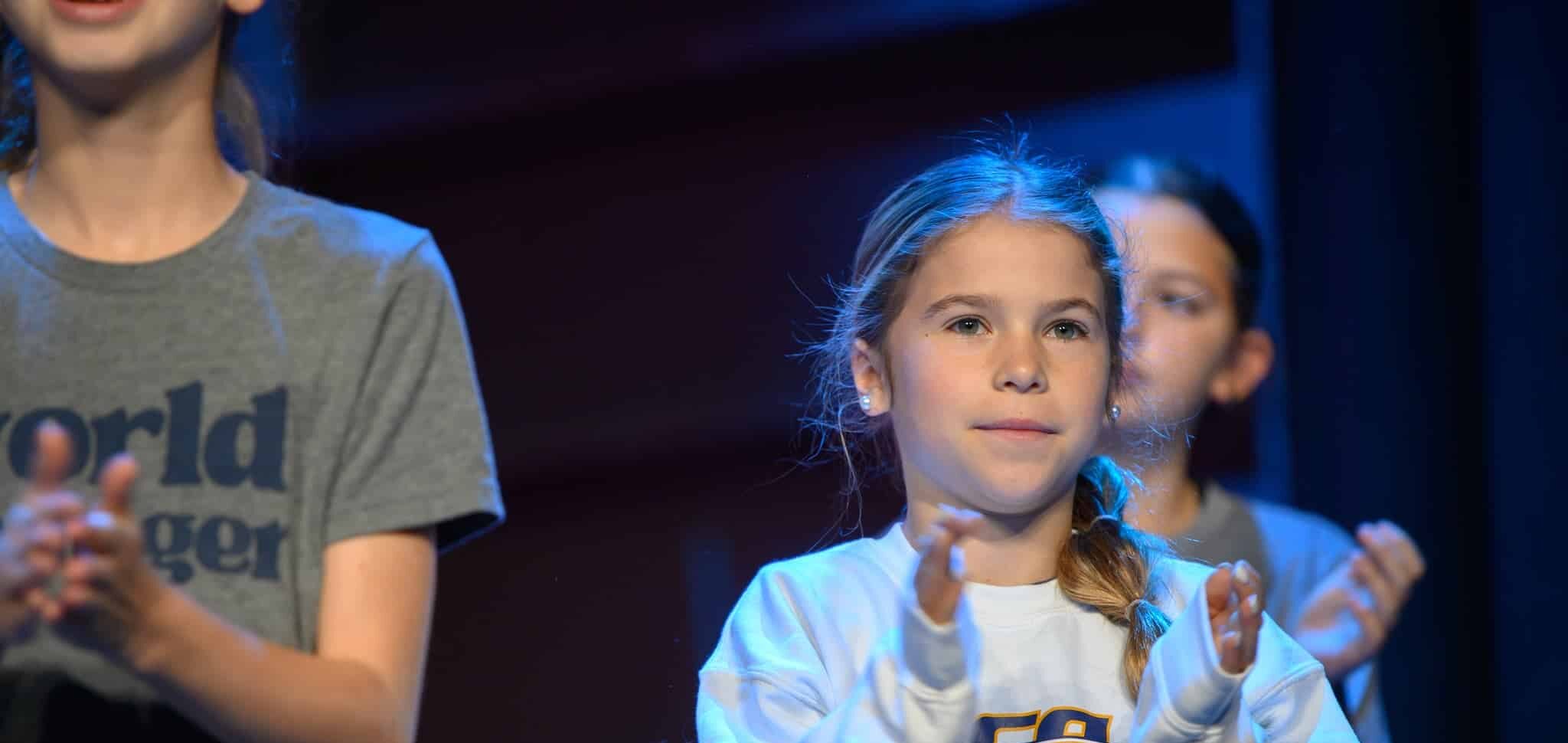 HCA elementary student on stage clapping