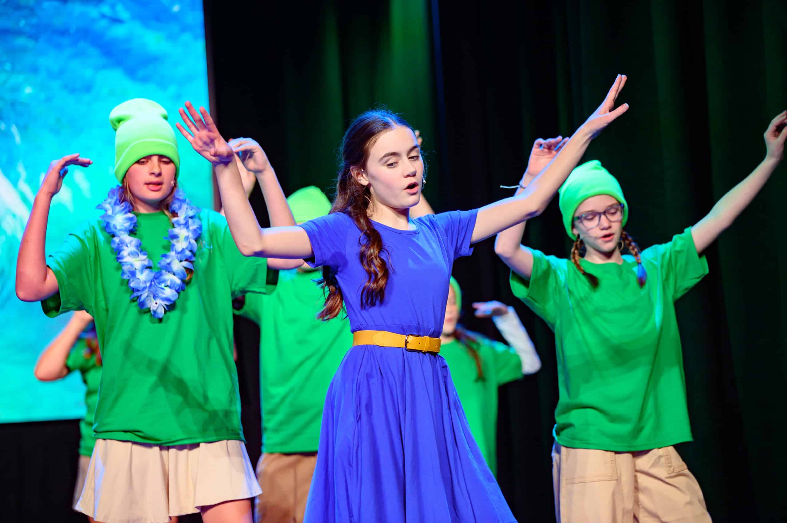HCA students performing in musical in blue and green outfits