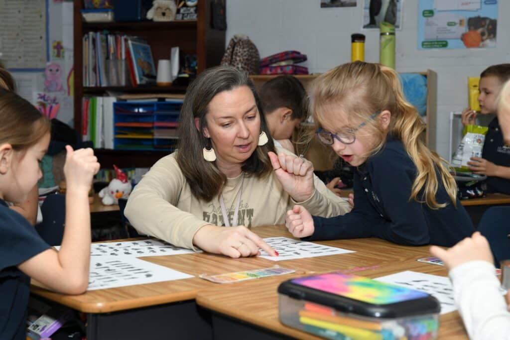 HCA teacher and elementary student looking at paper with images on it.