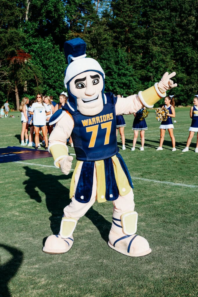 HCA mascot on field with cheerleaders in background